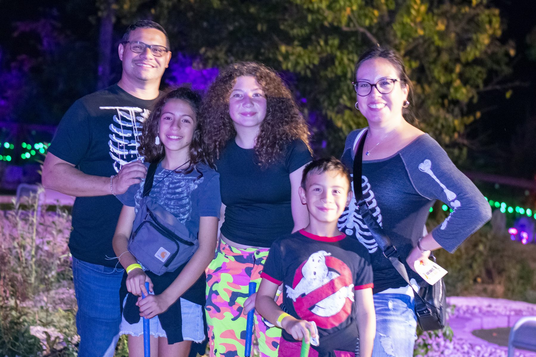 A family walking the glowing pumpkin trail after dark